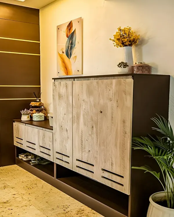 This entryway features a custom-designed shoe cabinet with distressed wood-finish doors. The unit provides both concealed and open storage for shoes, keeping the entrance neat and tidy.