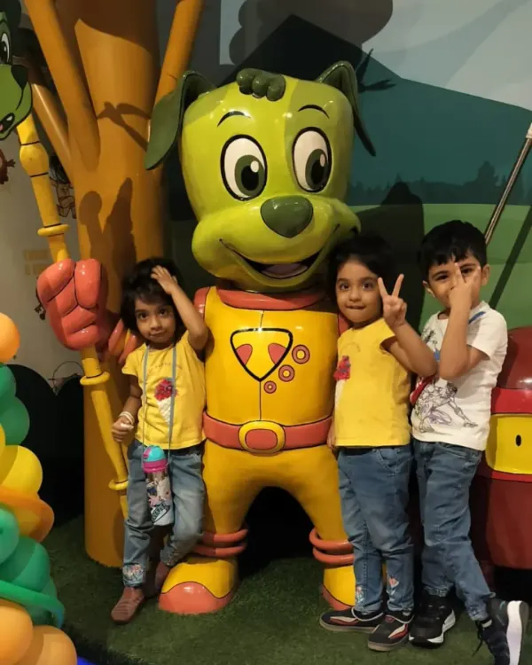 Three young friends pose with our main mascot, Tinga Dojo. These character interactions are a highlight for many of our visitors.