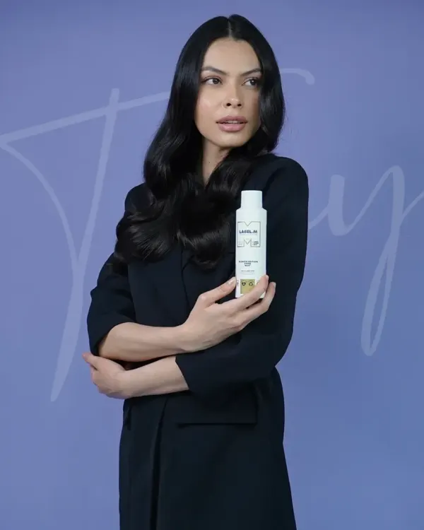 The final touch. After creating beautiful soft waves, our stylist holds up the Label.M product used to achieve the look, showcasing the professional tools we use to protect hair and ensure long-lasting style.