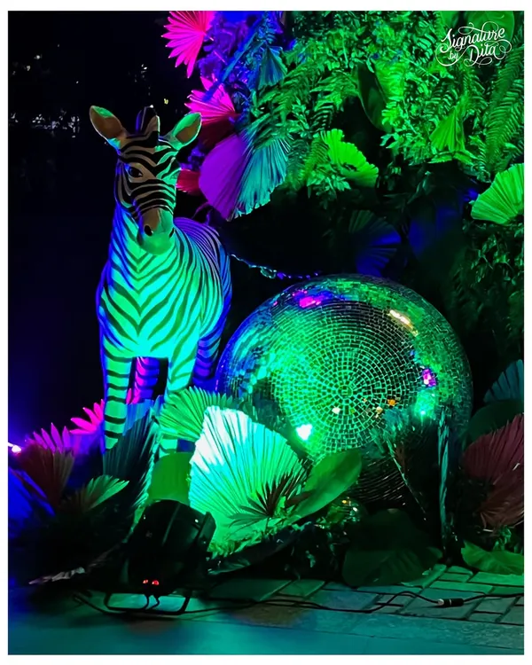 This is the energy I love to create. For this 'Neon Jungle' birthday, I combined lush greenery with vibrant UV lighting, a life-sized zebra prop, and a giant disco ball to craft an immersive, high-energy party atmosphere reminiscent of Studio 54.