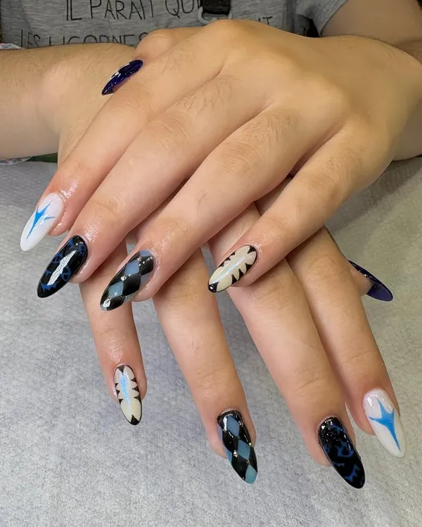 A bold and graphic nail art look for a client who wanted something unique. This set features a mix of patterns, including argyle, abstract flames, and starbursts, all in a striking black, white, and blue color palette.