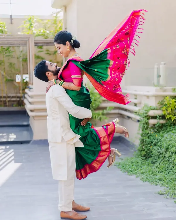 A playful and dynamic shot of Amit lifting his fiancée Asawari during their outdoor engagement shoot. Her green and pink saree adds a beautiful pop of color.