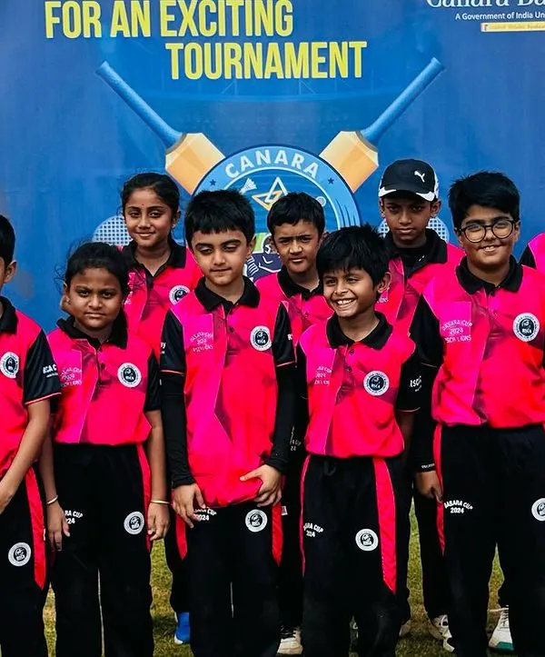 The Under-10 team, featuring both boys and girls, poses proudly in front of the Canara Bank Premier League banner during the RSCA Dasara Cup.