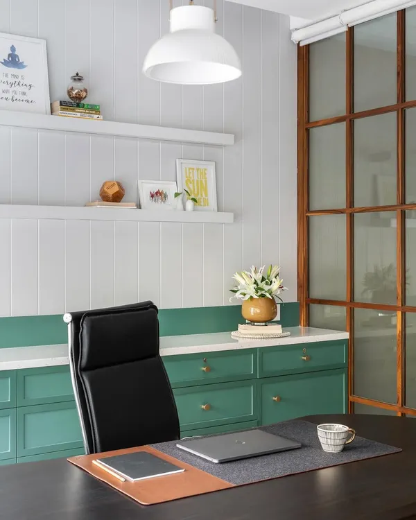 An executive cabin designed for focus and style. The combination of white paneled walls, green cabinetry, and a sleek black leather chair creates a professional yet inspiring environment.
