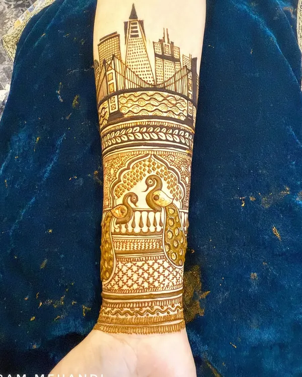 A close-up of a full arm design, showing the intricate jaali (net) and peacock patterns that complement the main cityscape theme.