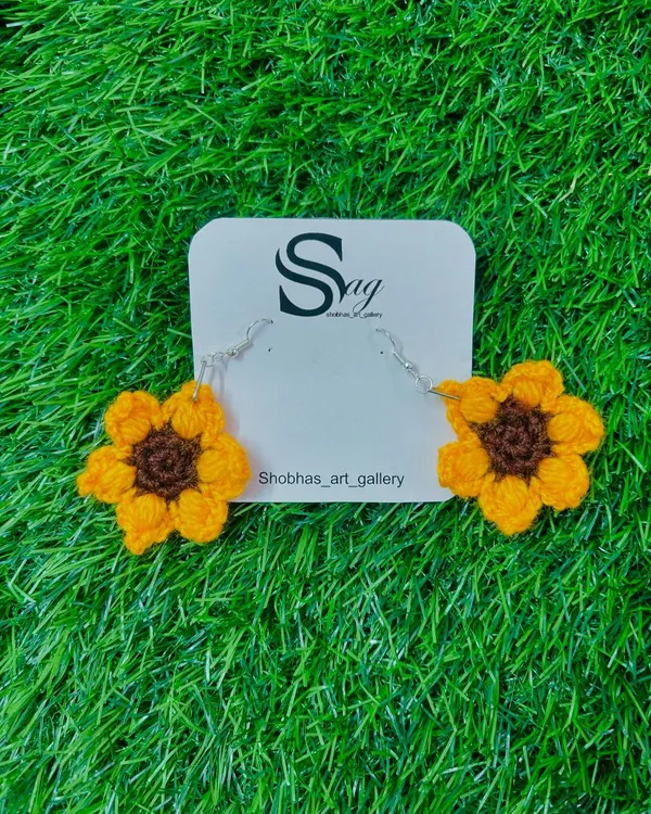 A pair of my cheerful sunflower crochet earrings. These handmade floral earrings are crafted with bright yellow and brown yarn, perfect for adding a touch of sunshine to your day.