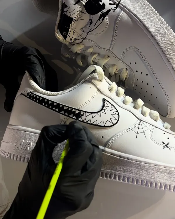 A close-up, behind-the-scenes shot of me hand-painting the fine details on a Halloween-themed custom sneaker.