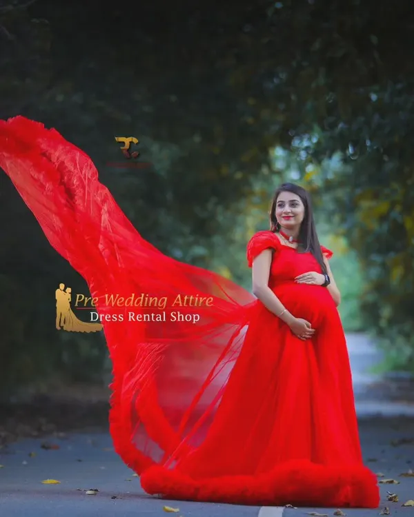 This vibrant red tulle gown is a showstopper, featuring a long, flowing train that creates incredible movement in photos. It's perfect for making a bold statement in both natural and urban settings, ensuring your maternity portraits are unforgettable.