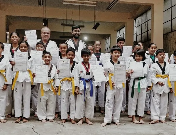 A group of our youngest students proudly displaying their new belts and certificates after a successful color belt exam. Their smiles show the joy of accomplishment.