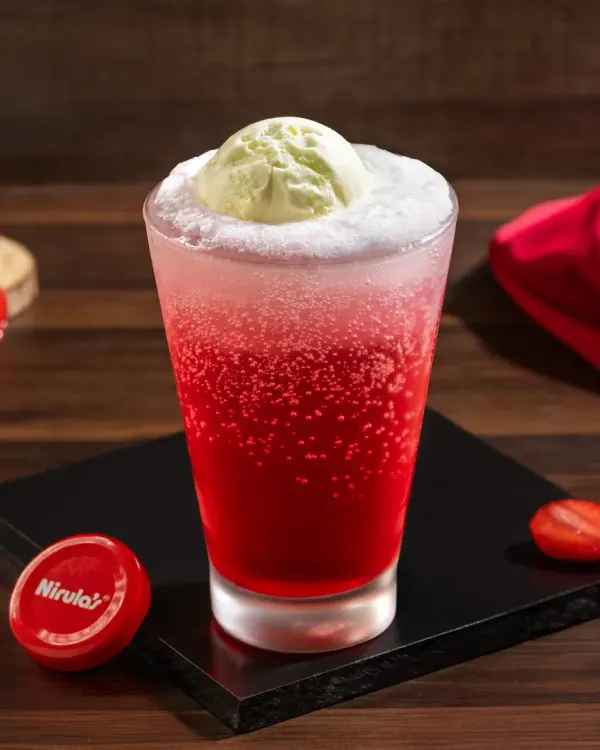 A vibrant strawberry ice cream soda, with a scoop of ice cream floating on top of a fizzy red drink.