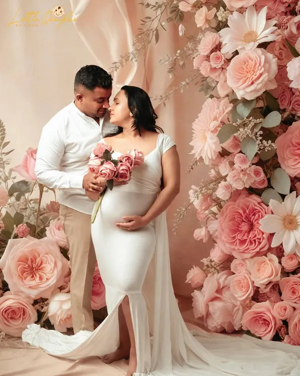 A romantic and dreamy maternity portrait with a beautiful floral backdrop. The soft lighting and the couple's tender embrace make this a truly timeless image.
