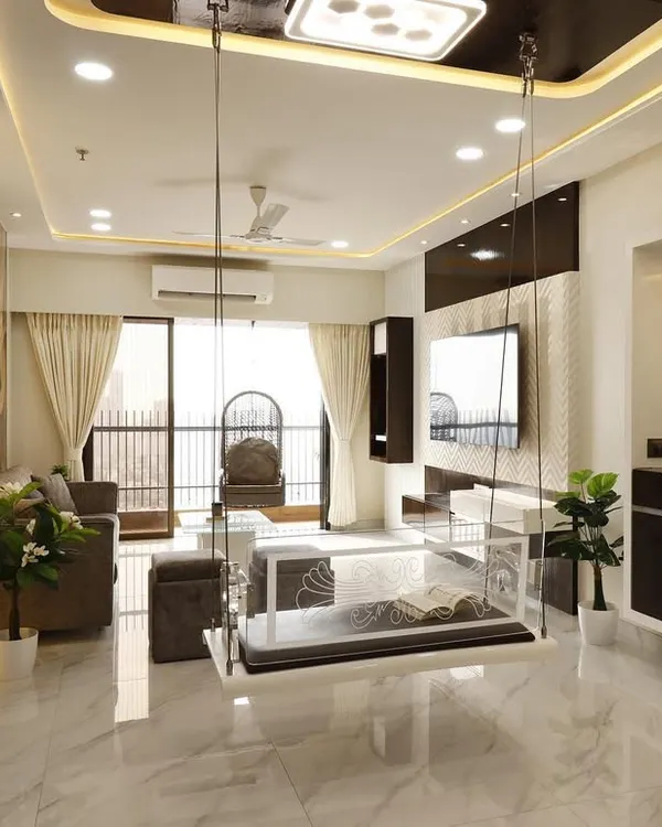 A clear acrylic indoor swing adds a touch of modern elegance without visually cluttering this spacious Malad living room. The design maintains an open feel, complemented by the marble flooring and sophisticated ceiling cove lighting.