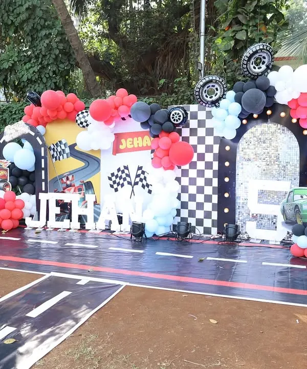 The main stage for a high-octane car-themed birthday party. I created a racetrack floor, a checkered flag arch, and used marquee letters for the birthday boy's name, Jehan, to make him feel like a racing star.