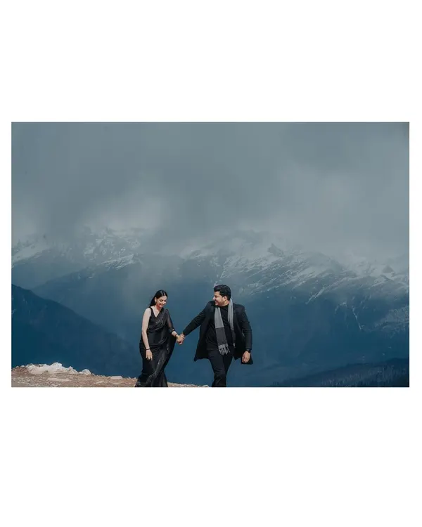 This image is a lesson in scale and drama. We'll teach you how to find locations where the mountains, covered in snow and clouds, create a powerful, panoramic backdrop, making the couple's simple walk feel like an epic journey.