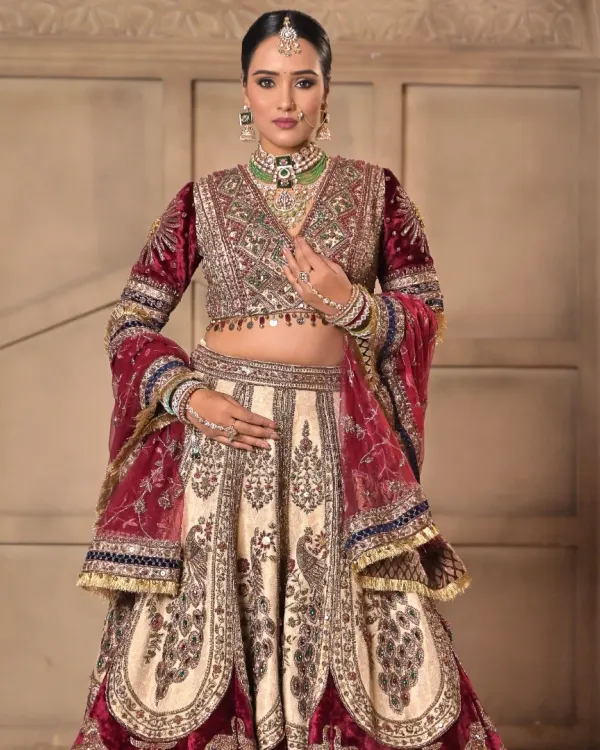 A full portrait of a royal bride. The makeup is designed to complement the rich velvet and intricate embroidery of her lehenga, with defined eyes and a soft, radiant base for a timeless day look.