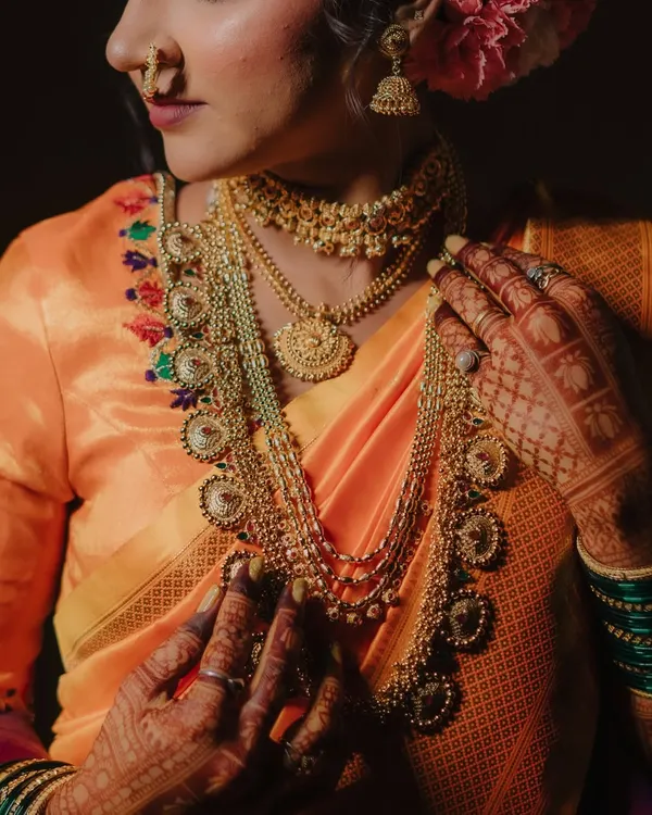 A detailed shot focusing on the bride's magnificent temple jewelry and the fine embroidery on her blouse, showcasing the artistry of her bridal look.
