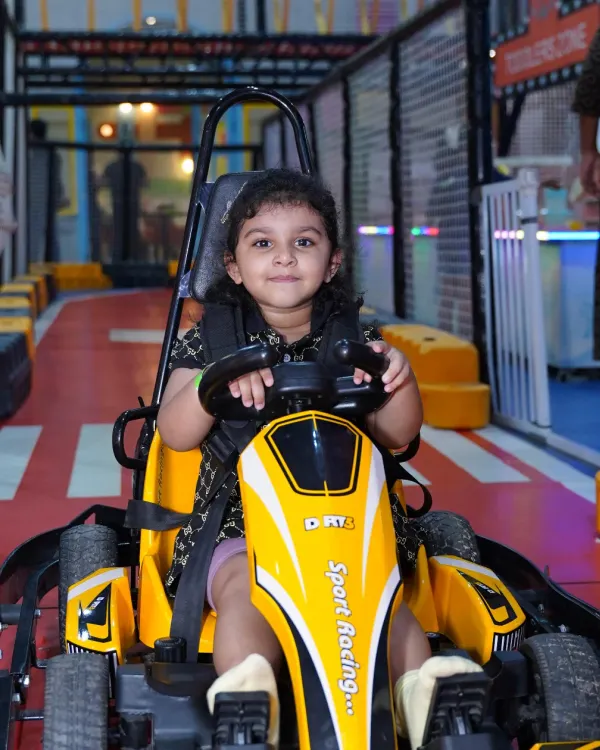 A young driver beams with excitement, ready to start her engine on our indoor go-kart track. The adjustable seats and safety harnesses ensure a perfect fit for kids.