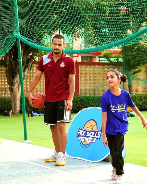 A coach's role is to be a mentor, strategist, and motivator. Here, I stand with a young player, ready to guide her through a drill. We are committed to comprehensive skill development and leadership.