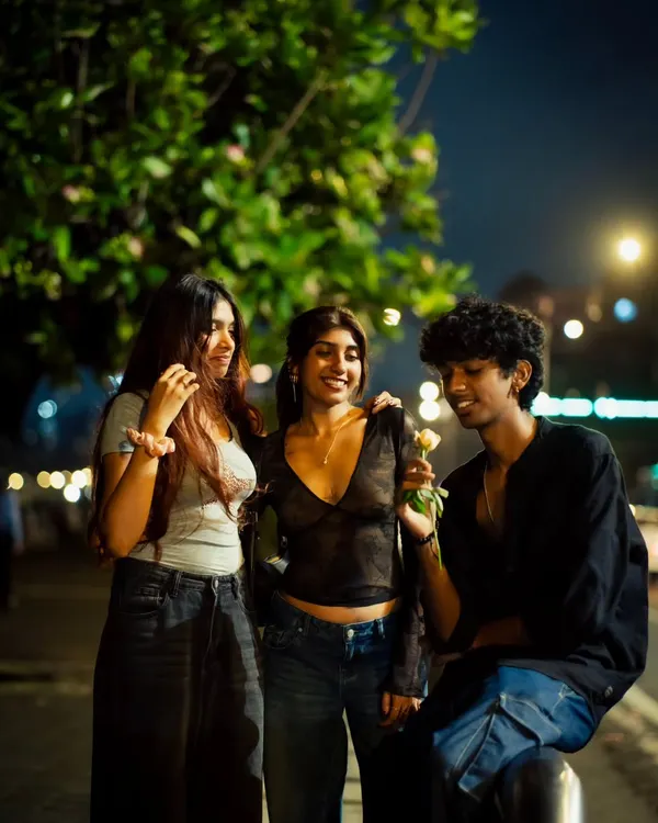 A candid moment between friends on a Mumbai street at night. The warm streetlights create an intimate atmosphere for this group portrait.