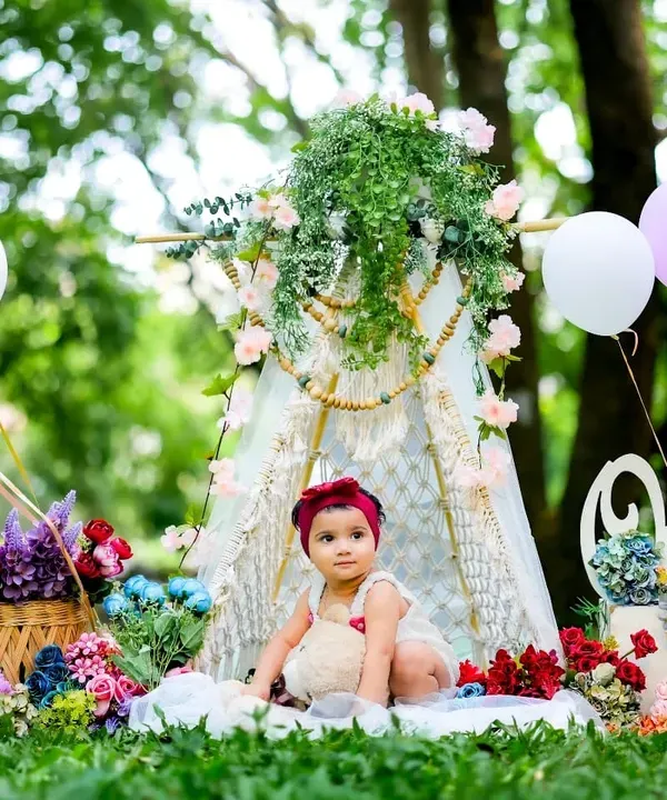 A fairytale scene in the park. This outdoor setup combines a floral teepee and balloons to create a magical first birthday portrait.
