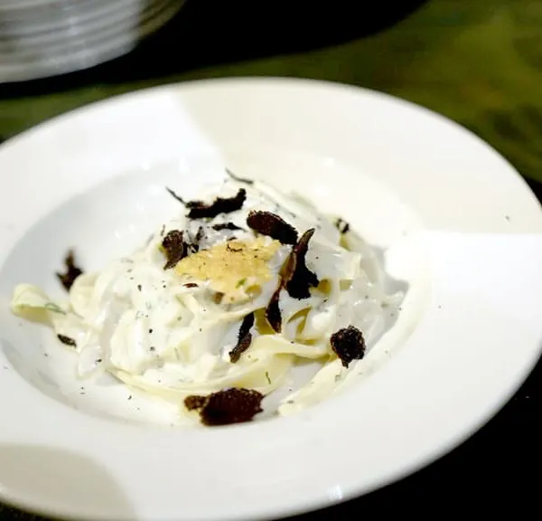 The final product of our Italian Pasta Studio. Freshly tossed fettuccine in a creamy Parmesan sauce, finished with generous shavings of French black truffle. A truly gourmet experience.
