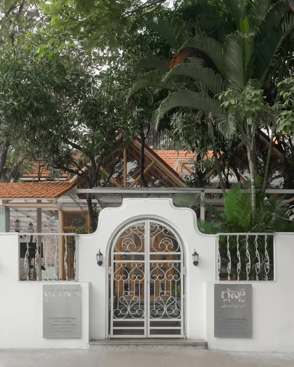 The entrance gate of the Bake House cafe, designed with an ornate arch that hints at the charming, glass-house-inspired structure within.