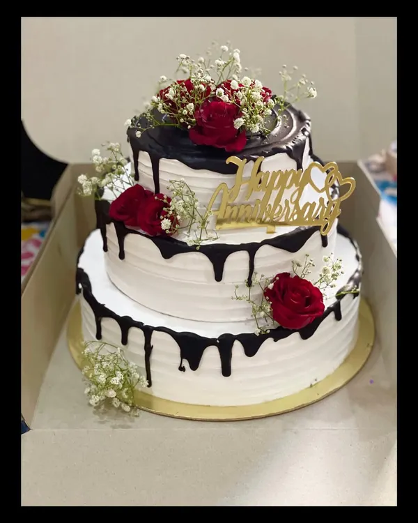 This five-kilogram, three-tier chocolate truffle cake was the centerpiece for a beautiful anniversary celebration. I love creating these grand cakes, decorating them with fresh roses and baby's breath for an elegant touch.