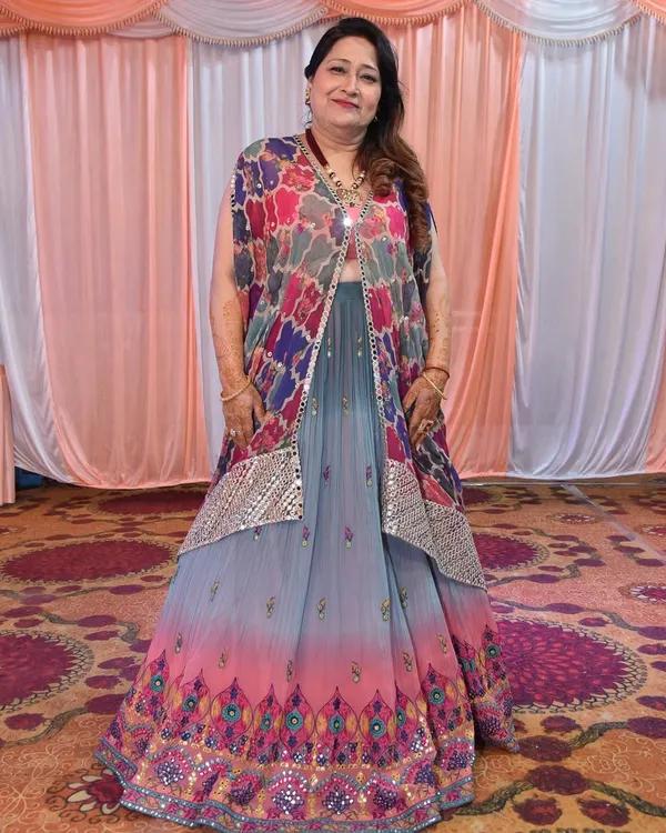 The mother of the bride looking radiant for her daughter's mehendi. We chose a vibrant, multi-colored lehenga with a stylish jacket and paired it with a bold necklace for a look that is both fun and elegant.