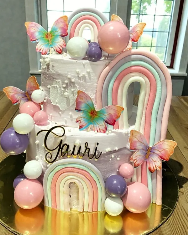 This two-tier butterfly and rainbow cake was a joy to create for a special first birthday. The bottom tier is a delicious Cookie & Cream, and the top is a rich Dutch Truffle, all completely eggless and decorated with buttercream.