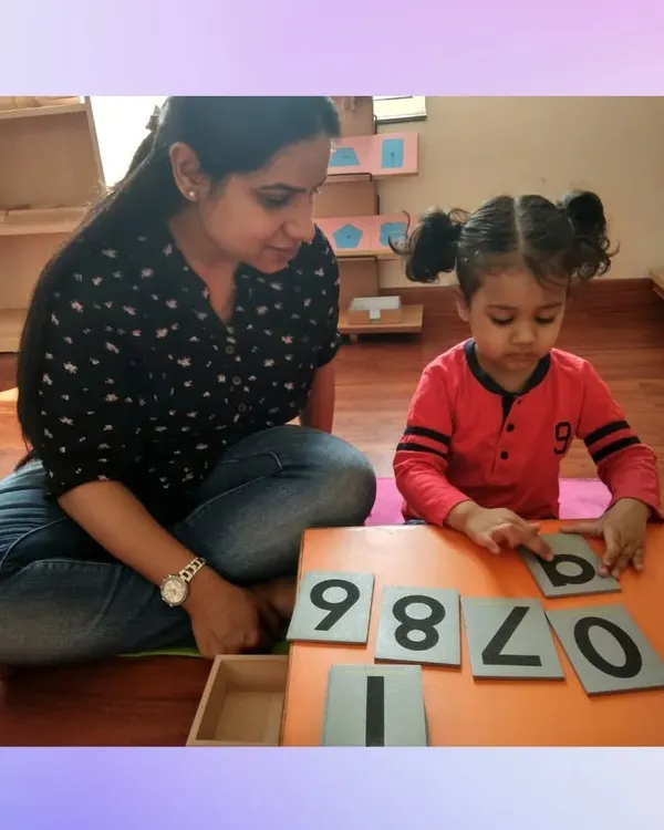 We believe learning should be a partnership. In this picture, one of our educators guides a child through number recognition using sandpaper numerals, a classic hands-on Montessori tool that makes abstract concepts tangible and engaging for young minds.
