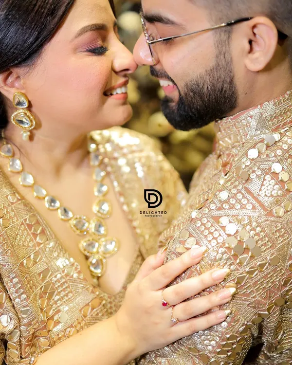 A close-up shot during a Roka ceremony, focusing on the couple's happy expressions and the intricate details of their matching gold outfits. These are the joyful, candid moments I love to capture.