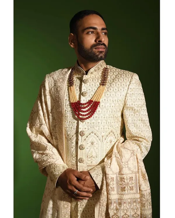 A detailed view of the craftsmanship on my ivory chikankari sherwani. The texture of the hand embroidery and the quality of the raw silk fabric are central to creating this regal piece, perfect for a discerning groom.