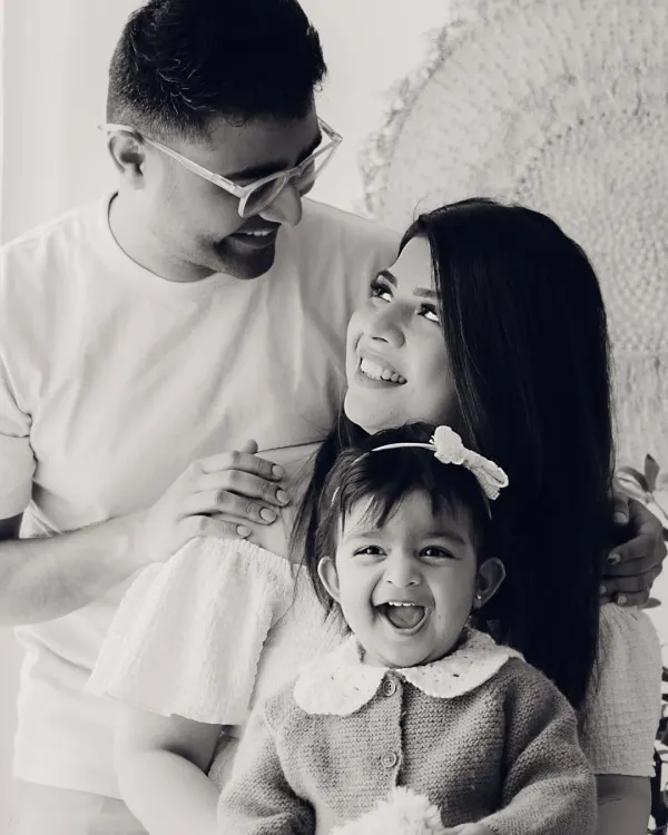 A joyful family portrait in black and white. The baby's wide-mouthed laugh is the center of this happy moment.