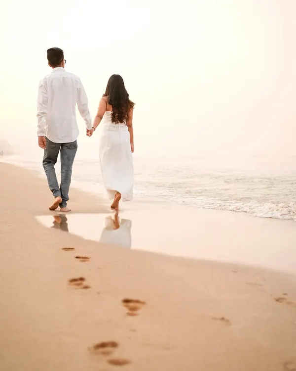 A beautiful, simple moment of a couple walking along the shoreline, leaving footprints in the sand as they start their new journey.