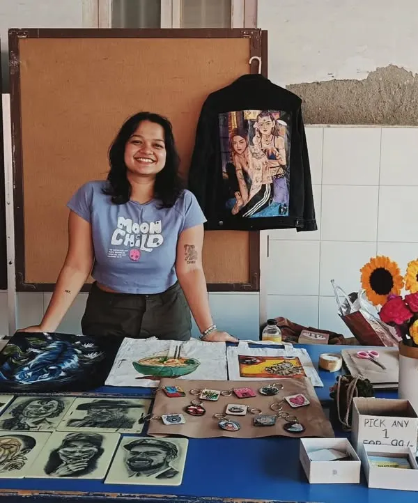 This is me at my stall during a local college festival. I love connecting with people in person and showing them the range of my hand-painted apparel and art prints.