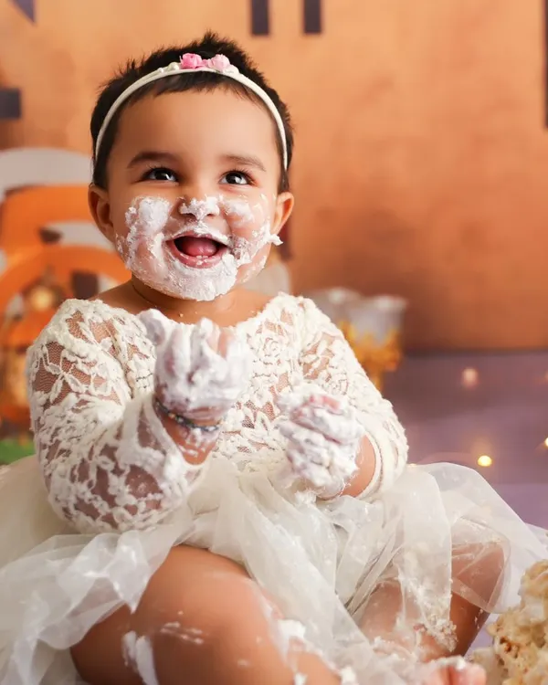 Capturing a moment of pure delight during a cake smash, with a happy, frosting-covered smile that says it all.