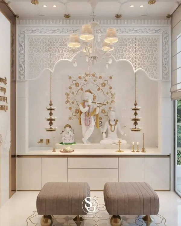 A luxurious and serene pooja room crafted from white marble with delicate floral inlay work. This space is designed for extended prayer and features a statement chandelier, traditional hanging lamps, and integrated seating.