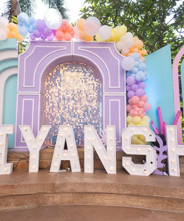 The main stage for Viyanshi's "Under the Sea" birthday party. The pastel arches and shimmering backdrop create a magical underwater palace feel, personalized with large marquee letters.