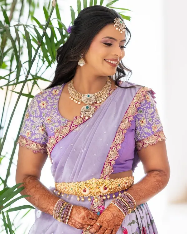 A smiling bride in her custom lilac langa dhavani, featuring a beautifully embroidered blouse and delicate detailing.