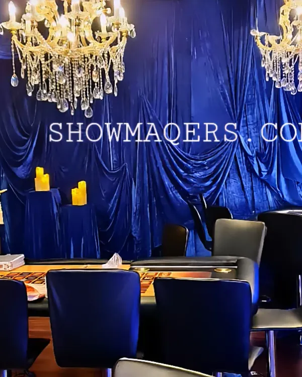 A luxurious setup for a Diwali cards party, featuring a professional casino table set against a backdrop of royal blue velvet drapes and crystal chandeliers.