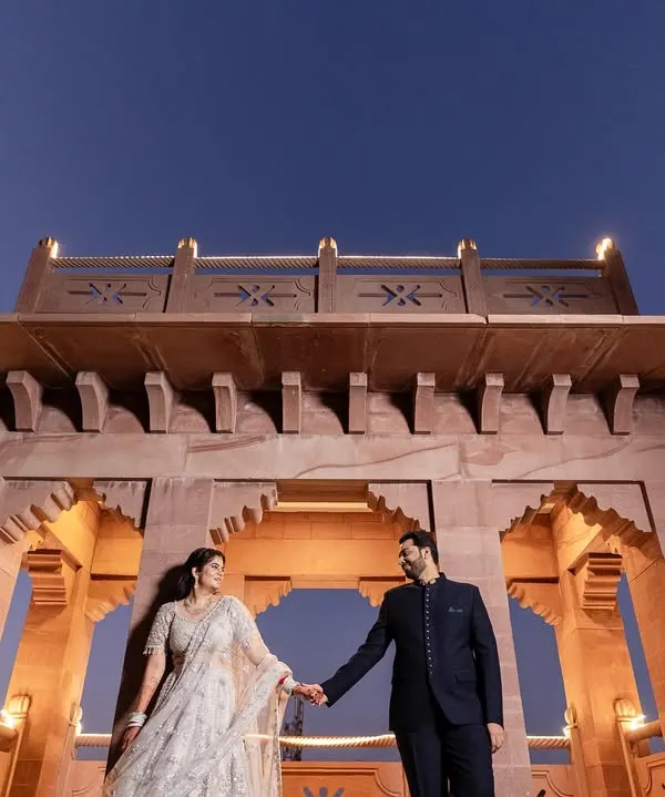 A dramatic, low-angle shot of the couple against a magnificent sandstone structure. We use architectural elements to create powerful and cinematic couple portraits.