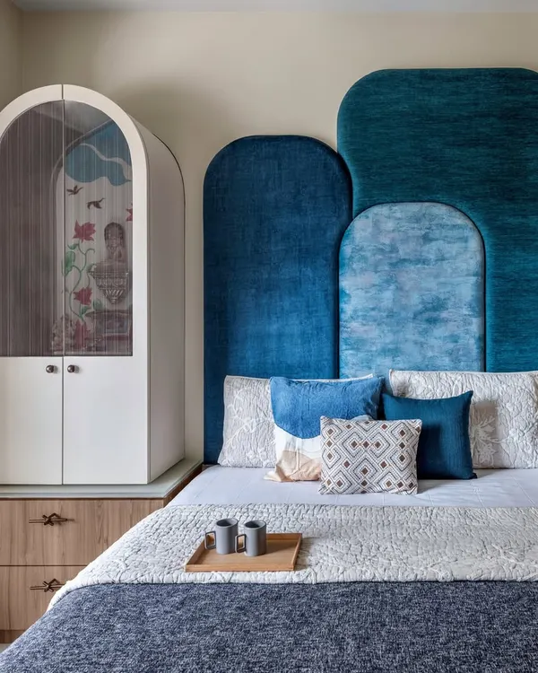 Designing for Mumbai homes pushes your creativity. In this guest bedroom, I managed to fit a full-sized bed, a mandir, wardrobes, and extra storage, all while creating a special look with a bold blue headboard.
