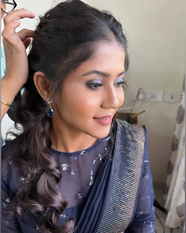 A modern party look featuring blue smokey eyes and a messy ponytail for Anuja. This is perfect for a cocktail party or reception.