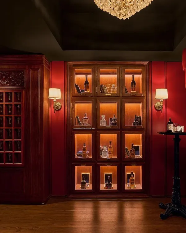 The "Vault" is the first room guests enter from a service elevator. This dramatic, all-red space features vintage chandeliers and private liquor lockers, immediately setting a secretive and exclusive tone for the speakeasy experience.