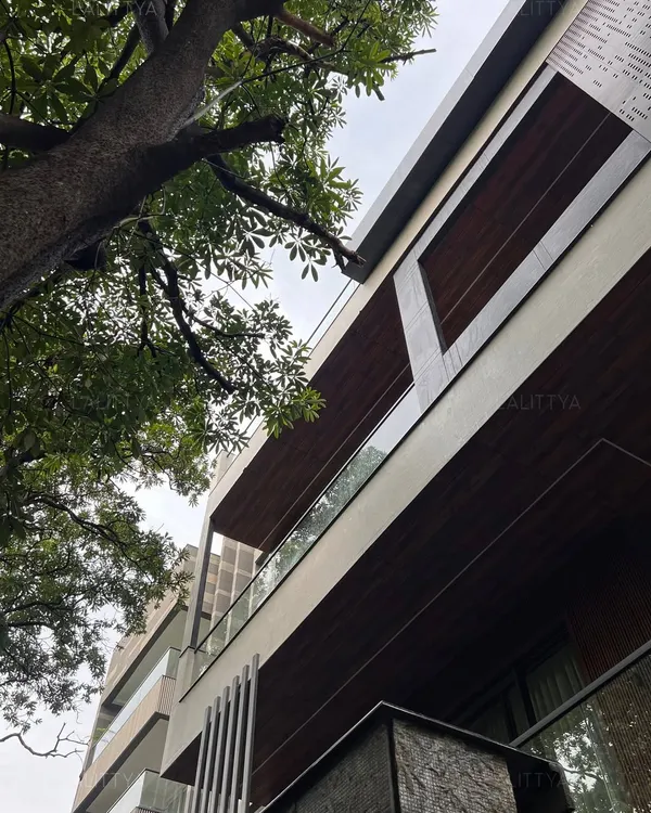 An upward view of a modern residence we designed, highlighting the cantilevered forms and the mix of materials. The warmth of the wood-paneled soffits contrasts with the clean white structure and glass railings, creating a dynamic and timeless facade.