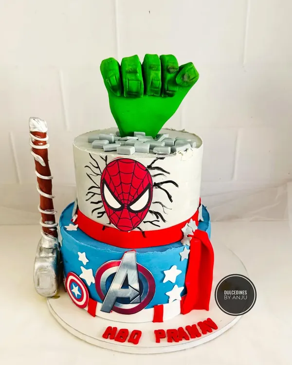 An action-packed two-tier Avengers cake. Featuring a Hulk fist smashing through the top, Thor's hammer, and Captain America's shield, this cake is a dream for any young superhero fan.