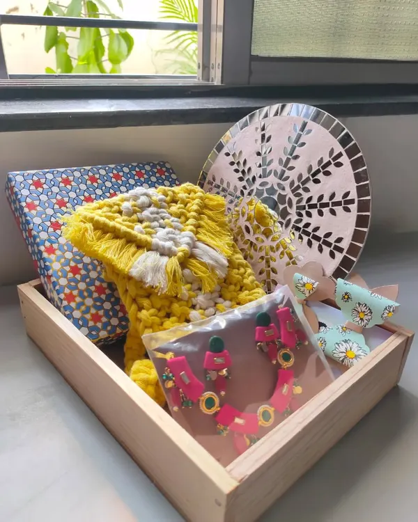 This is what a box of heartfelt gifts looks like. I curated this hamper with a handmade macrame purse, a mirror mosaic wall art piece, a colourful jewellery set, and some cute hair bows, all packed in a beautiful wooden tray.