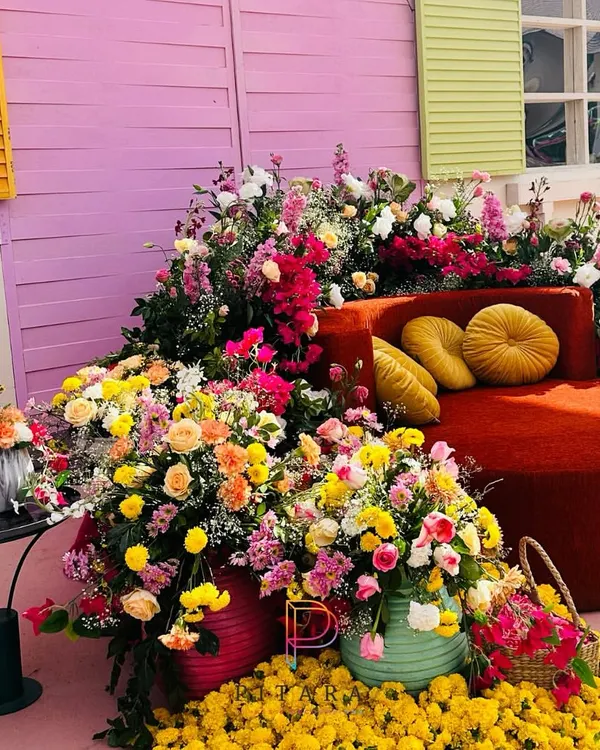 A Haldi that’s a riot of color. This seating area is surrounded by an explosion of marigolds, roses, and bougainvillea against a backdrop of colorful shutters, creating a joyful and picturesque setting.
