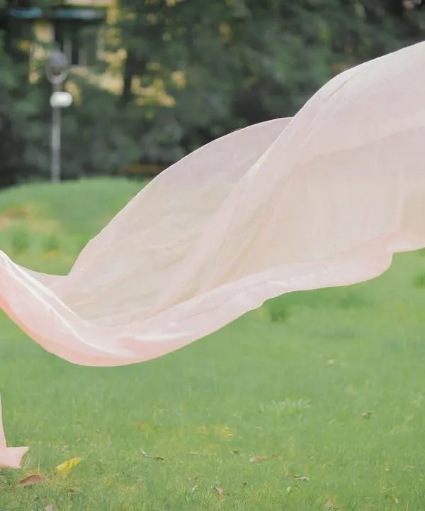The green lawn and soft light of the park provide the perfect canvas for this "flying dress" shot, creating a dreamy and romantic atmosphere.
