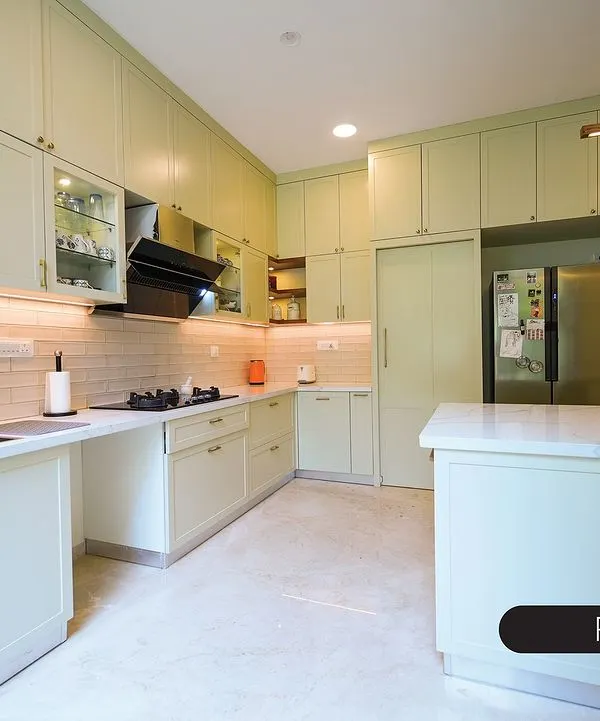 This spacious kitchen is bathed in a soft, pastel green, creating a calm and refreshing atmosphere. The shaker-style cabinets provide a timeless look, while the large island and seamless storage, including a hidden refrigerator, make it incredibly functional.